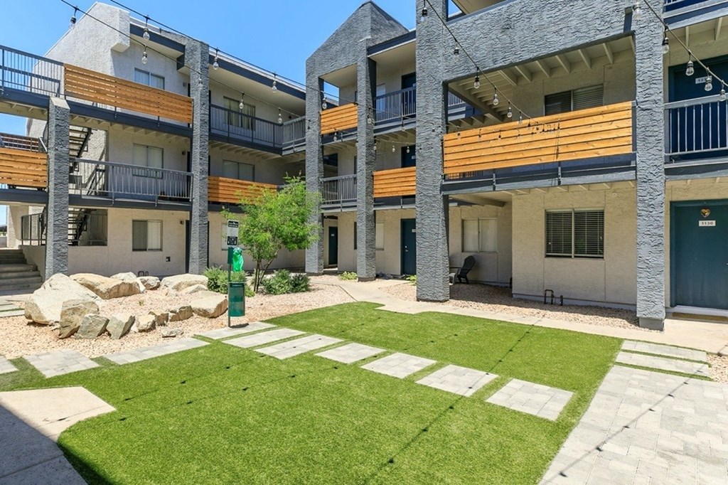 A modern apartment complex with a green lawn in the courtyard.