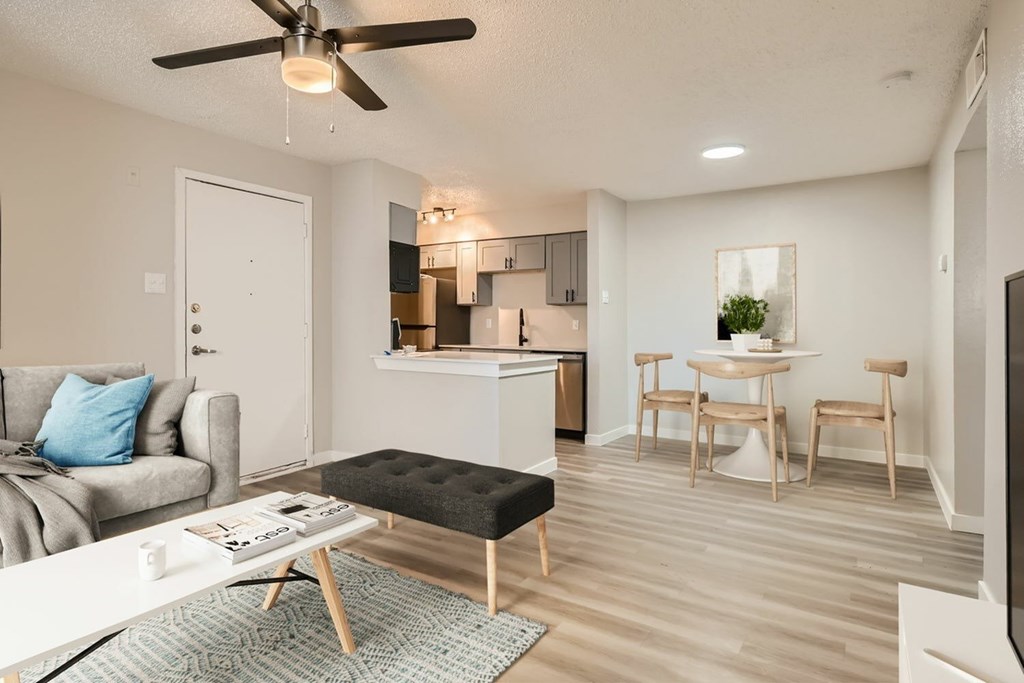 A living room with a grey couch, a white coffee table, and a black ottoman.