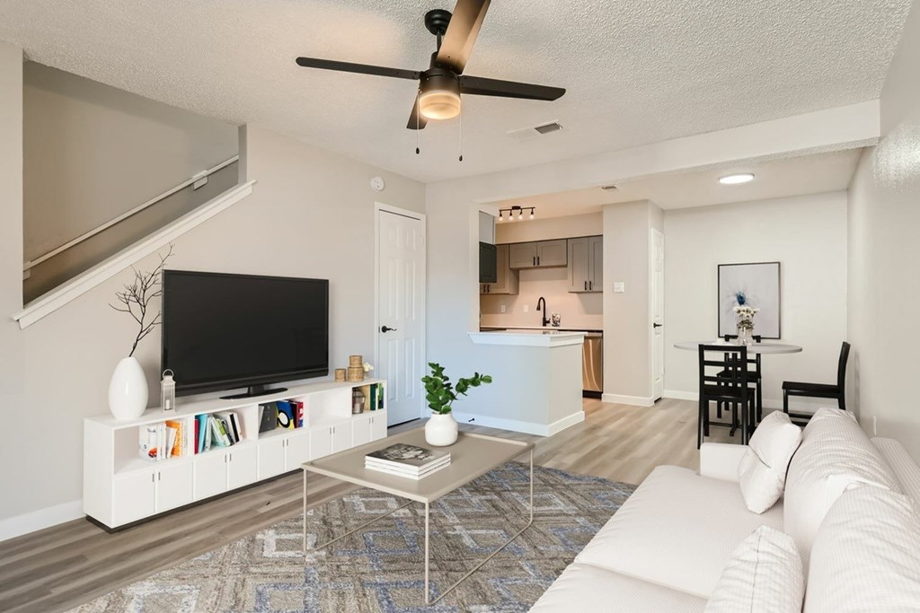 A living room with a white couch, a television, and a ceiling fan.