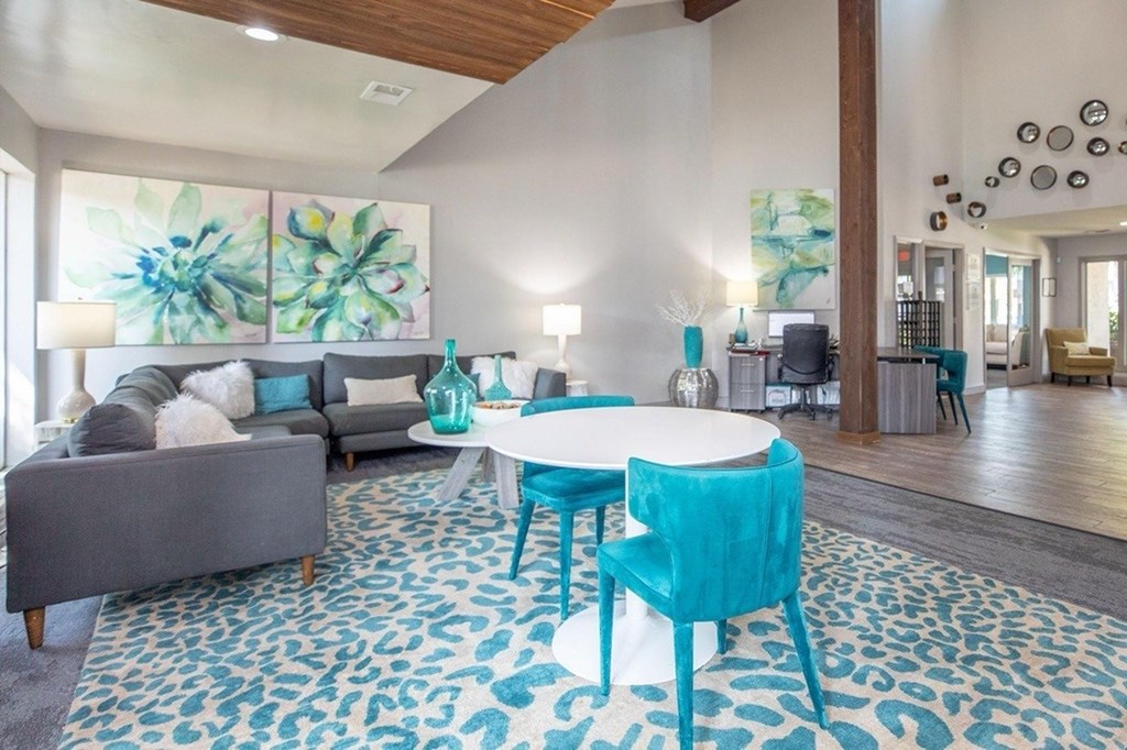 A living room with a grey couch, a white table, and blue chairs.