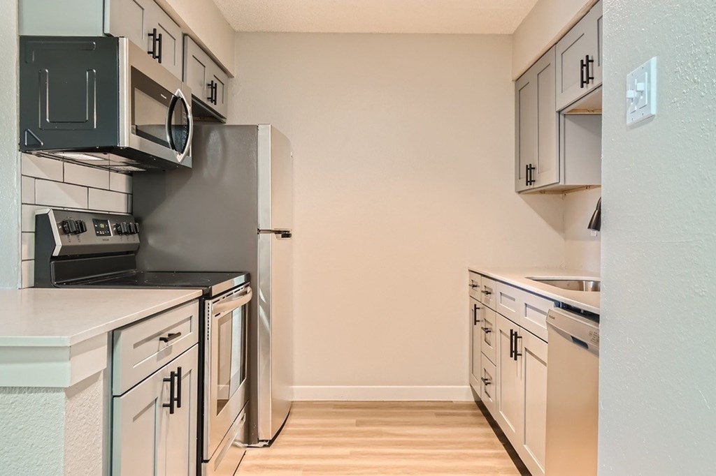 A kitchen with a black stove top oven and white cabinets.