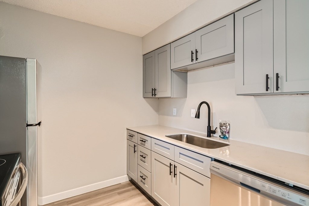 A kitchen with a sink, dishwasher, and refrigerator.