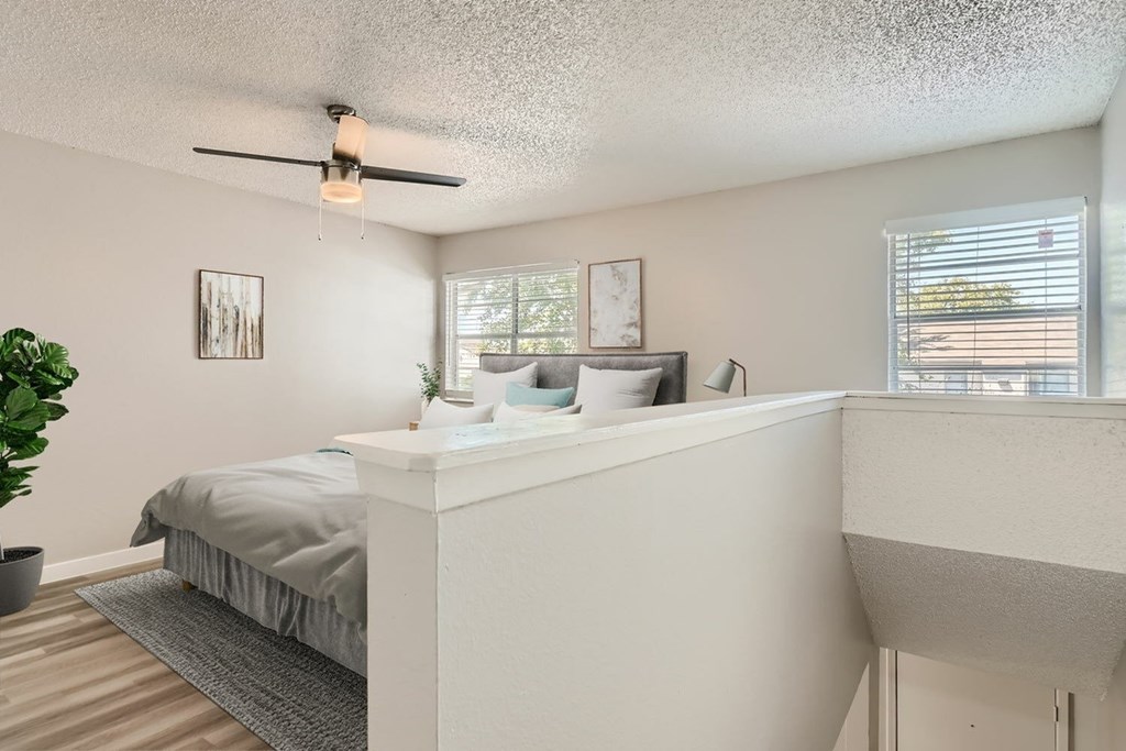 A bedroom with a bed, a nightstand, and a ceiling fan.