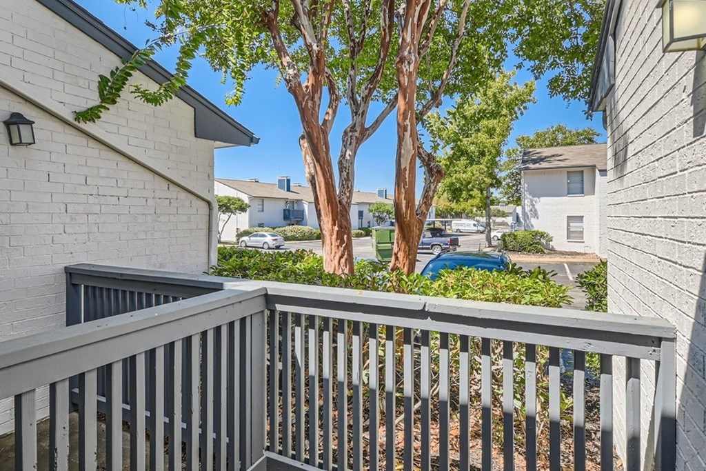 A balcony with a railing overlooks a tree and a street.