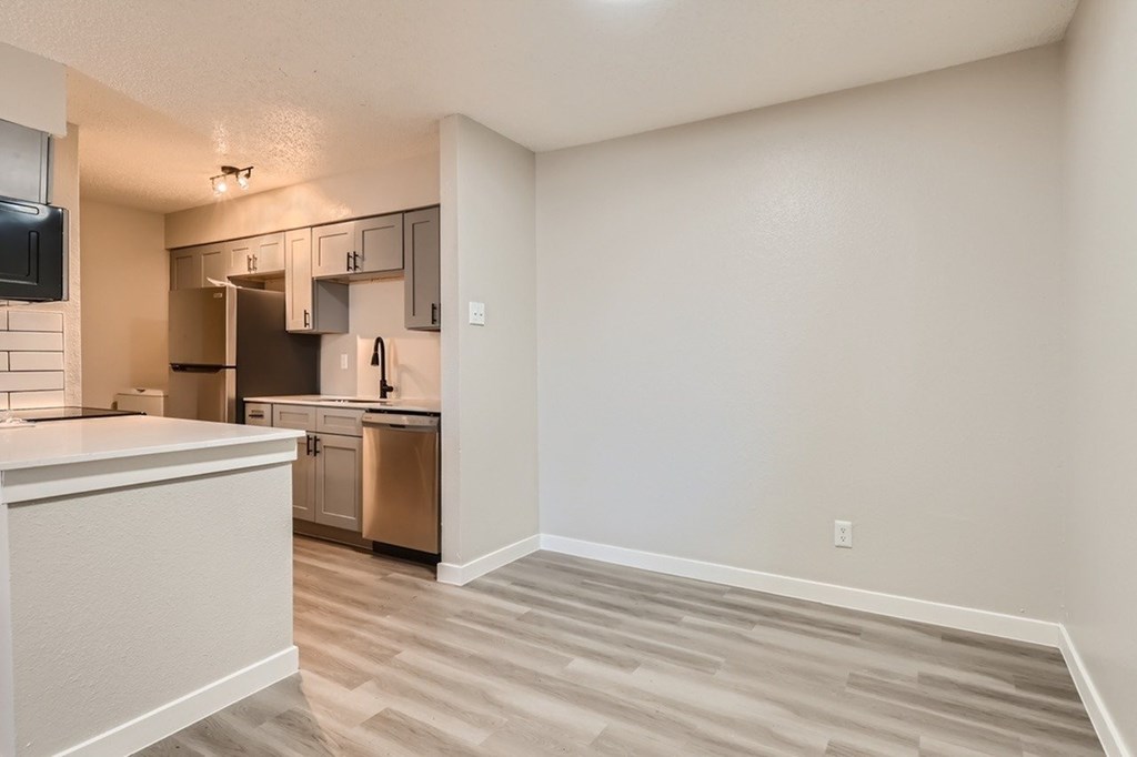 A kitchen with a white counter top and a microwave on the wall.
