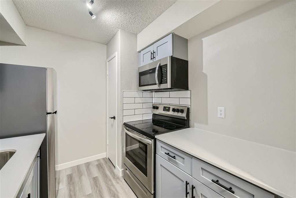 A kitchen with a black fridge, black oven, and black microwave.