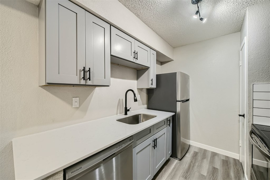 A kitchen with white countertops and grey cabinets.