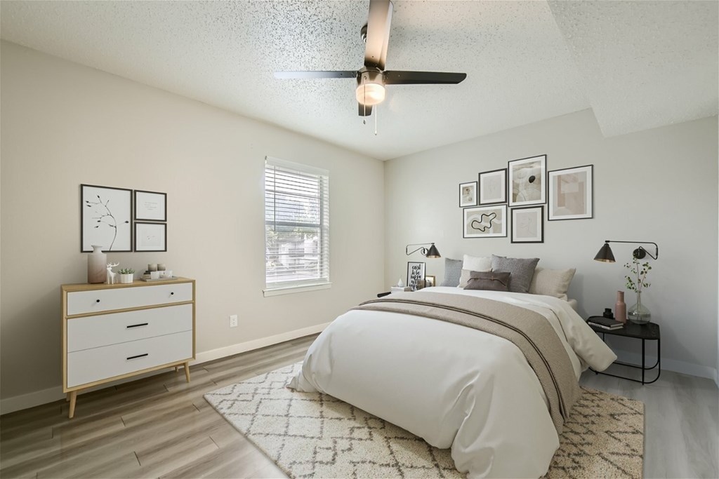 A bedroom with a large bed, a dresser, and a ceiling fan.