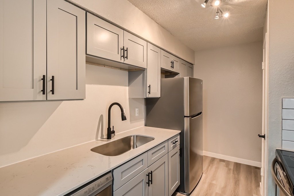 A kitchen with white cabinets and a stainless steel refrigerator.