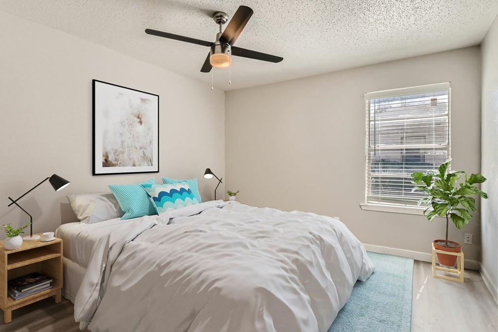 A bedroom with a bed, a ceiling fan, and a window with blinds.