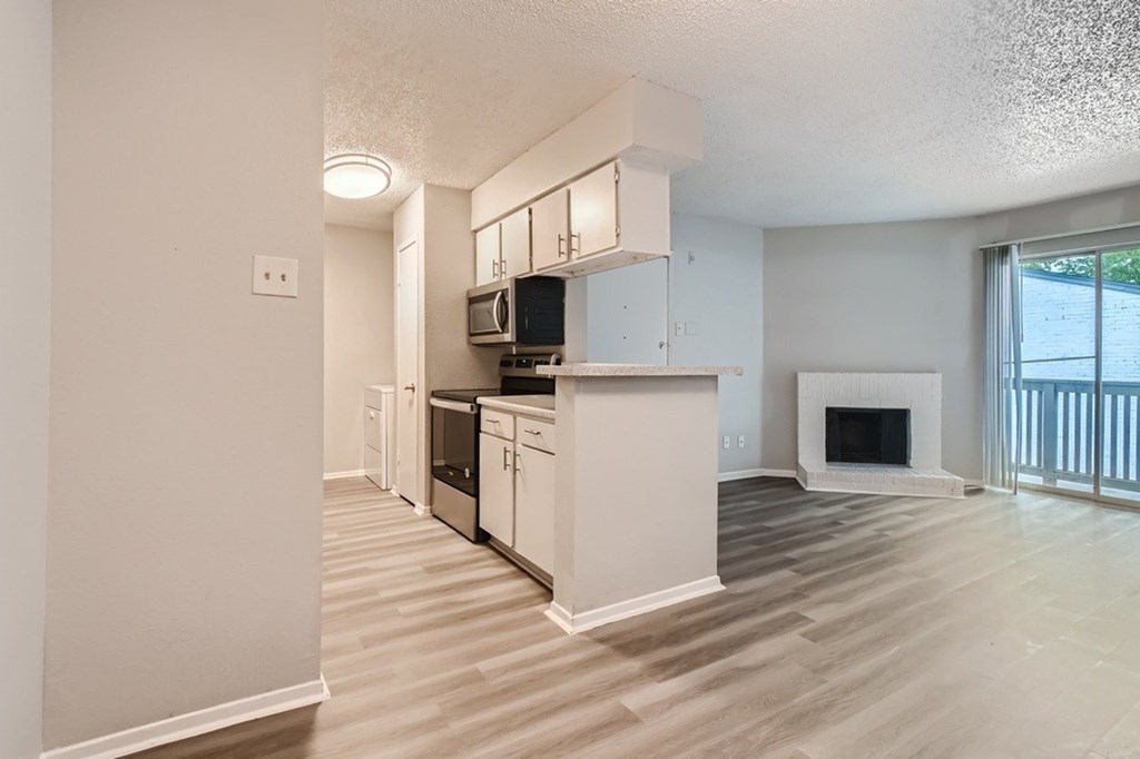 A kitchen with white cabinets and a fireplace in a living room.