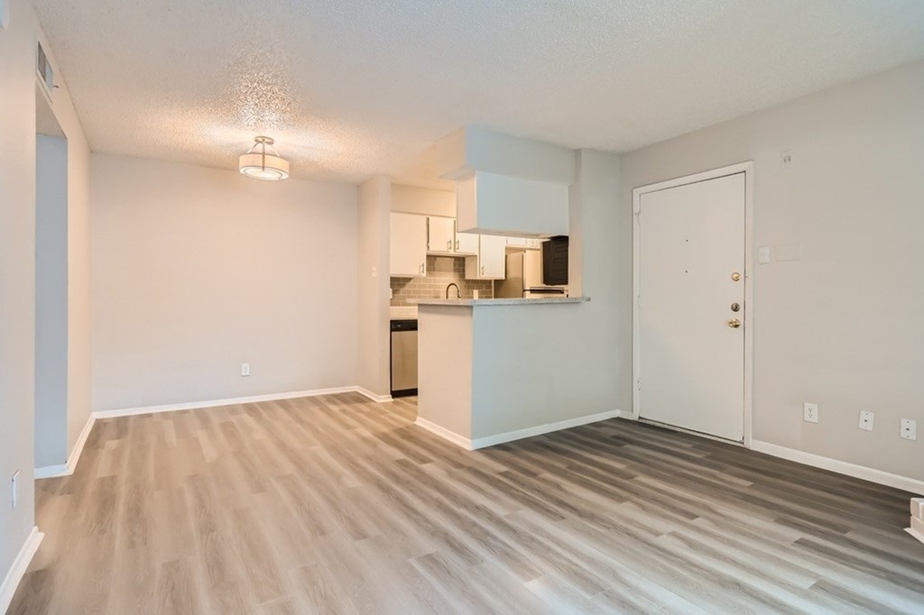 A kitchen area with a white door and a white cabinet with a black countertop.