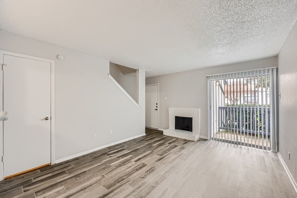 A white door is on the left of a room with a fireplace and a window.