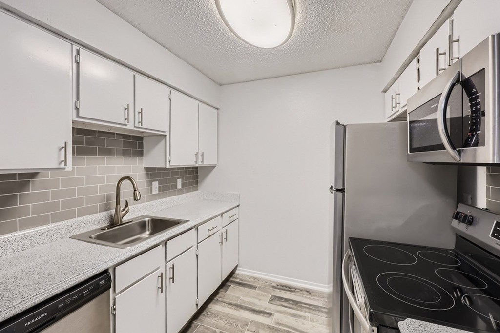 A kitchen with white cabinets and a black dishwasher.