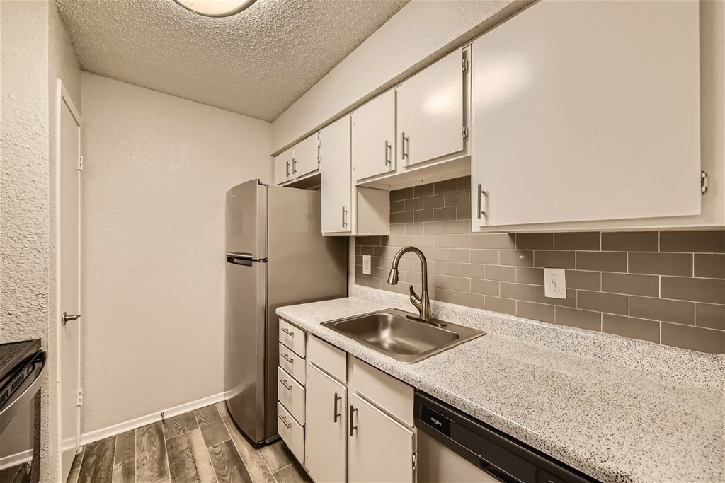 A kitchen with white cabinets and a black counter.