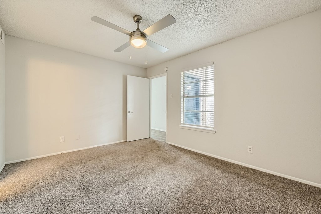 A room with a ceiling fan and carpeted floor.