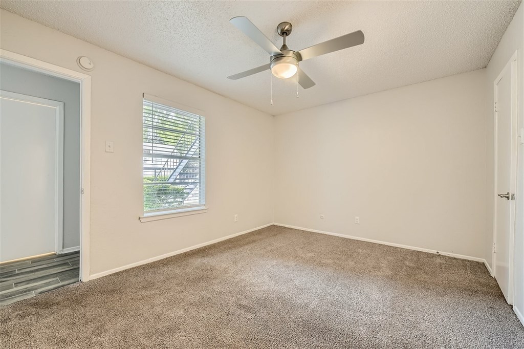A room with a ceiling fan and carpeted floor.