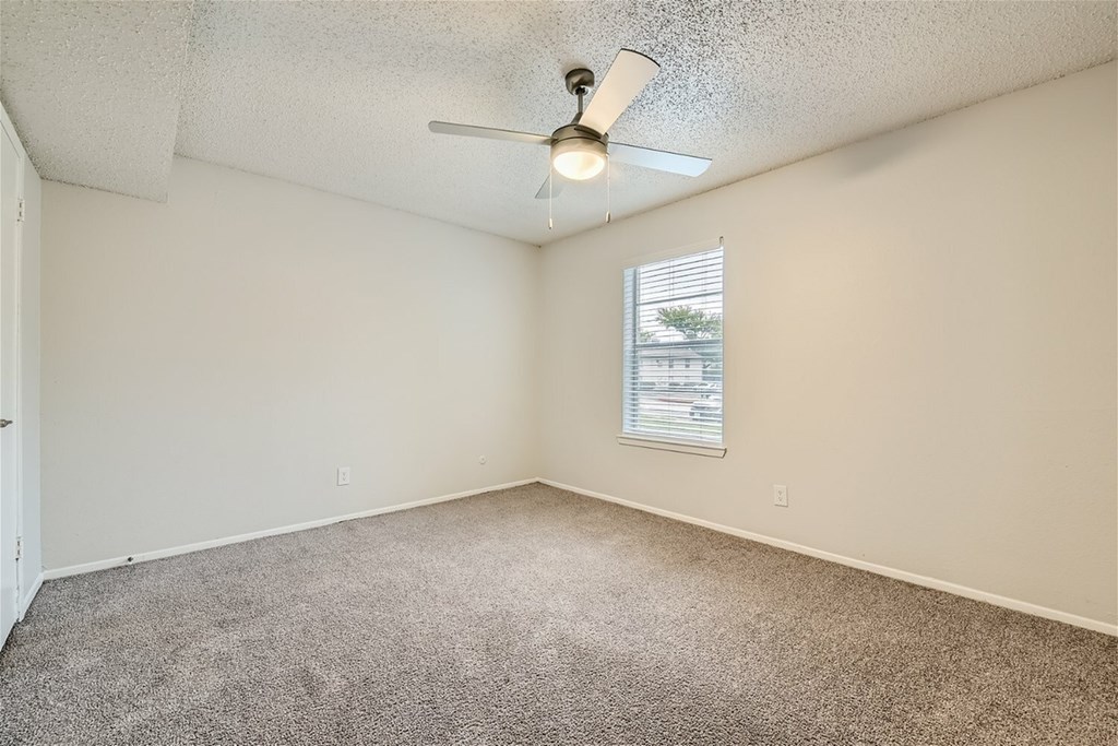 A room with a ceiling fan and a window with blinds.
