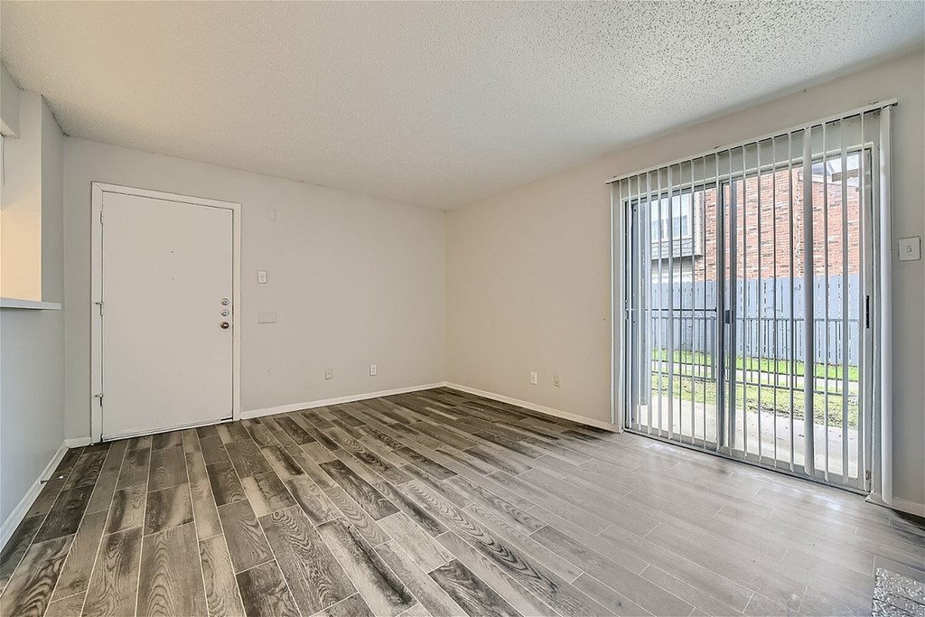 A room with a ceiling fan and a kitchen area in the background.