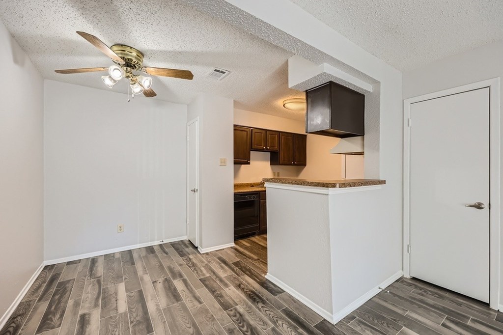 A room with a ceiling fan and a kitchenette.