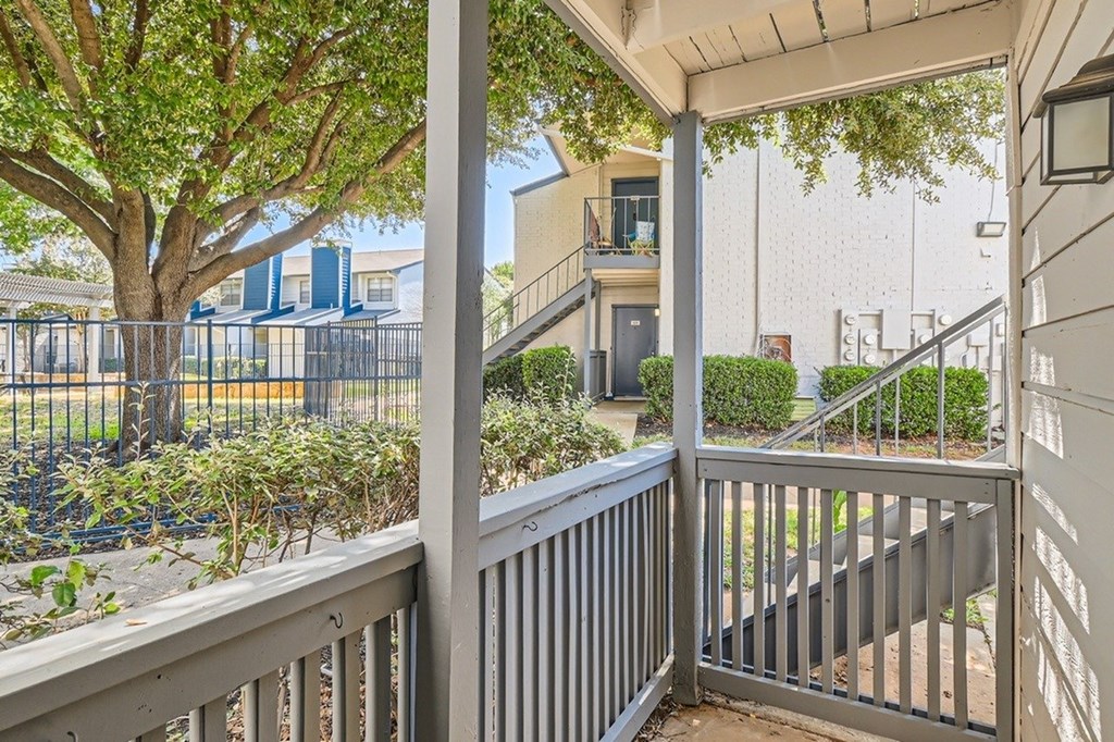 A balcony with a railing and a tree in the background.