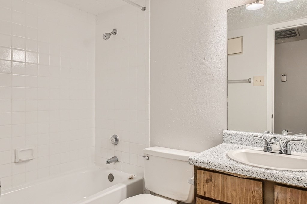 A white bathroom with a tub, sink, and mirror.