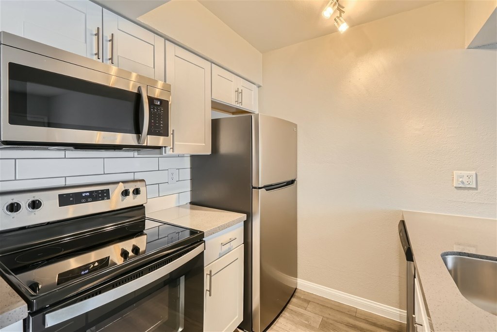 A kitchen with a stove, microwave, and refrigerator.