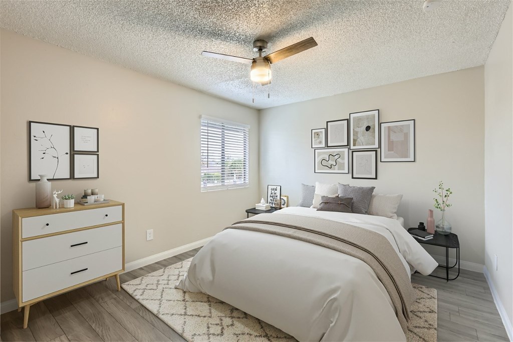 A bedroom with a bed, nightstand, and pictures on the wall.