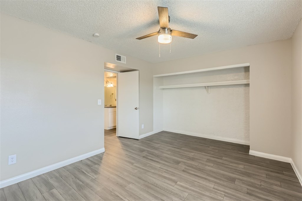 A room with a ceiling fan and light fixture, and a doorway leading to another room.