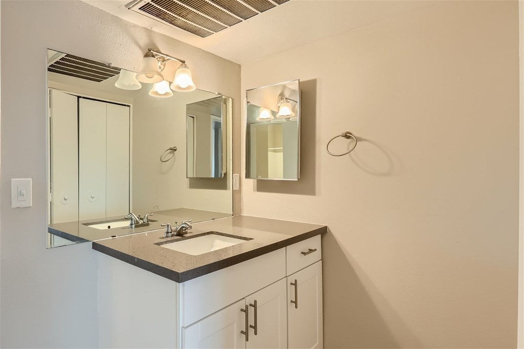 A bathroom with a sink, mirror, and light fixture.