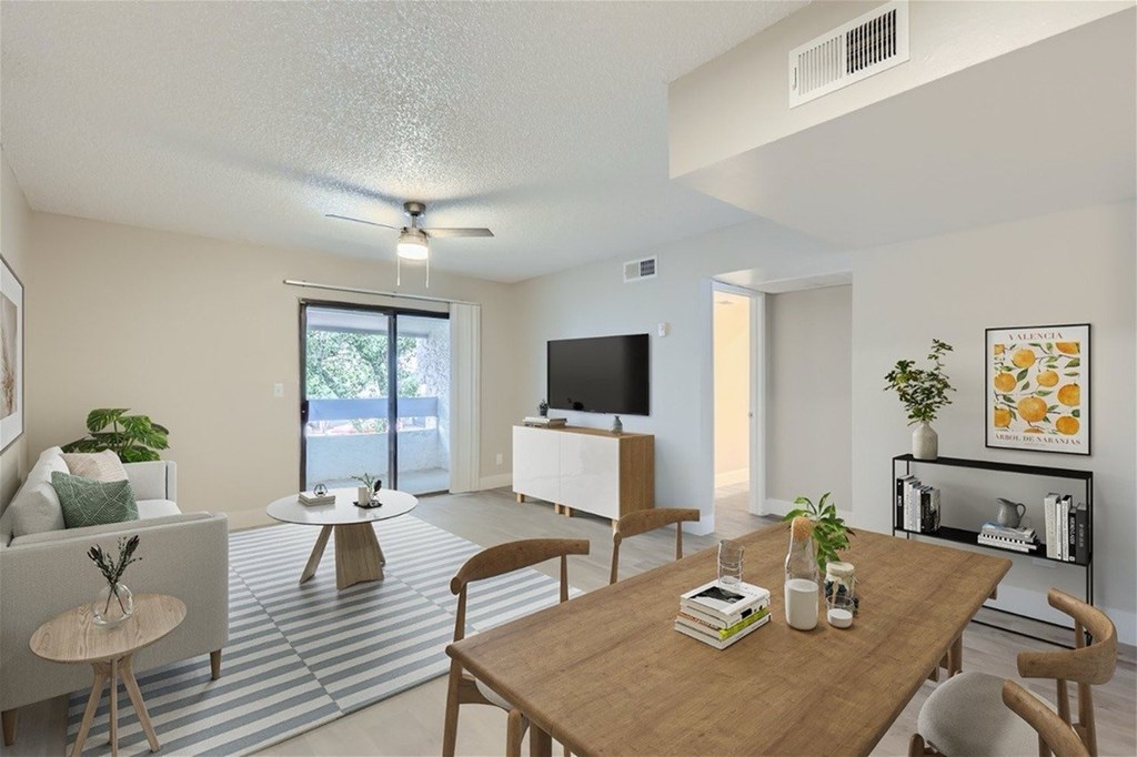 A living room with a television, a couch, a table, and a plant.