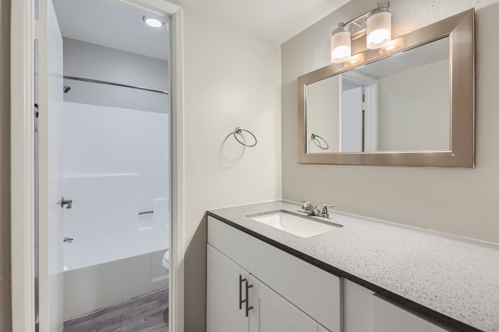 A bathroom with a sink, mirror, and shower.