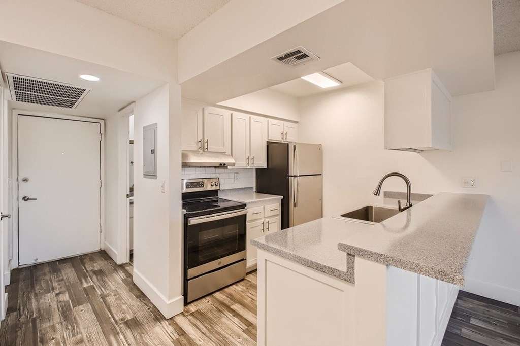 A modern kitchen with white cabinets and a wooden floor.