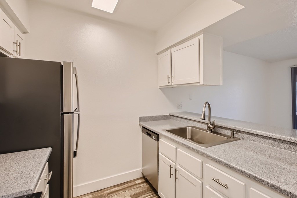 A kitchen with a black refrigerator and white cabinets.