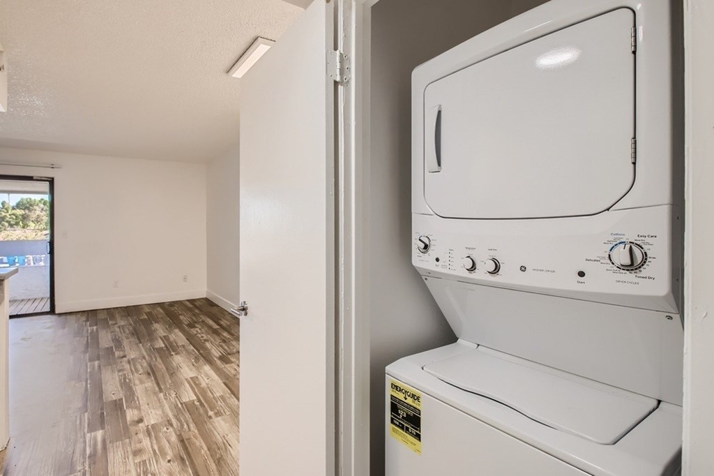 A white oven is in a room with wood flooring and a window.