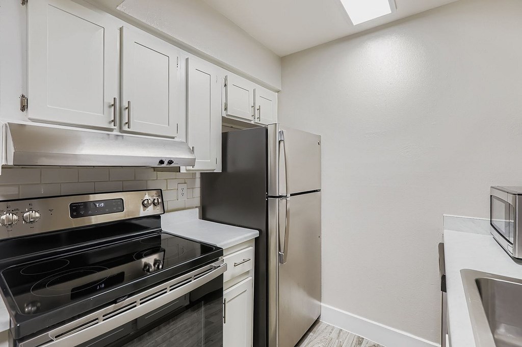 A kitchen with white cabinets and a wooden floor.