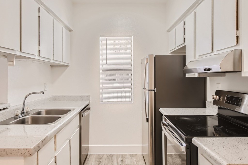 A kitchen with a sink, stove, and refrigerator.