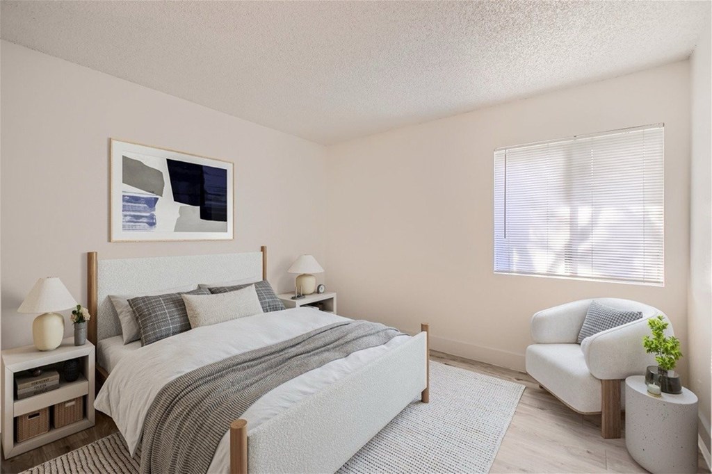 A bedroom with a large bed and a chair.