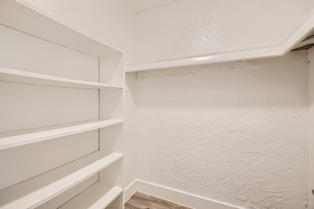 A white shelving unit in a room with white walls.