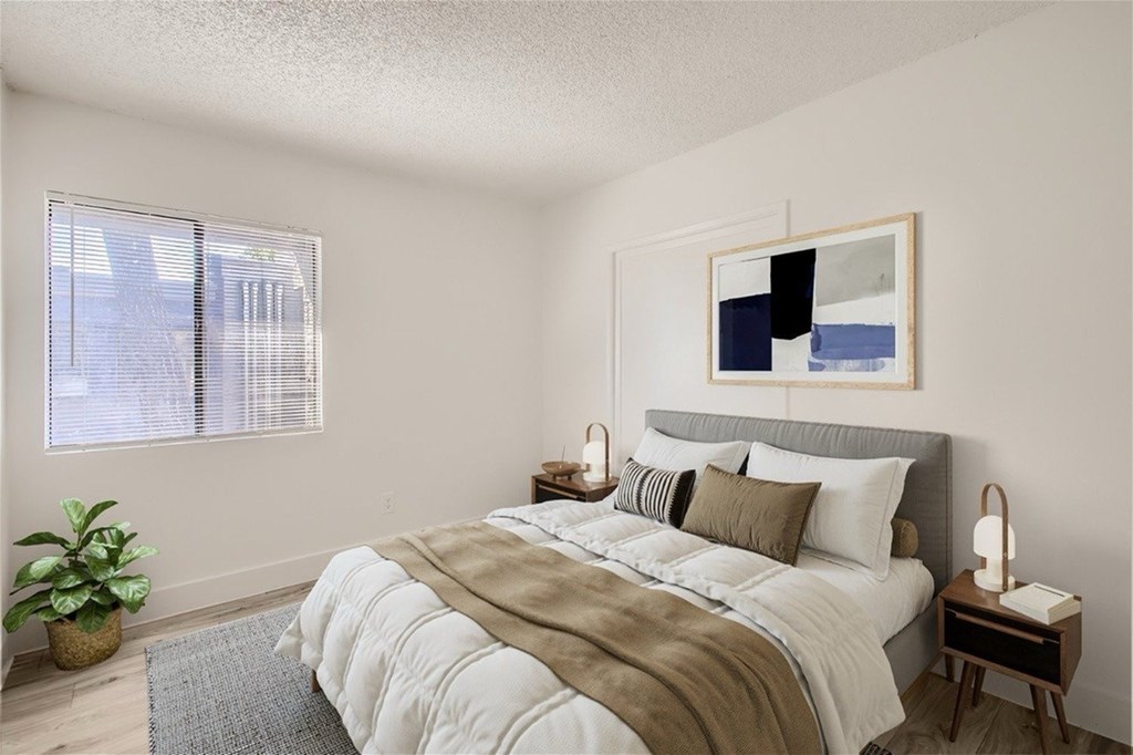 A bedroom with a large bed and a painting on the wall.