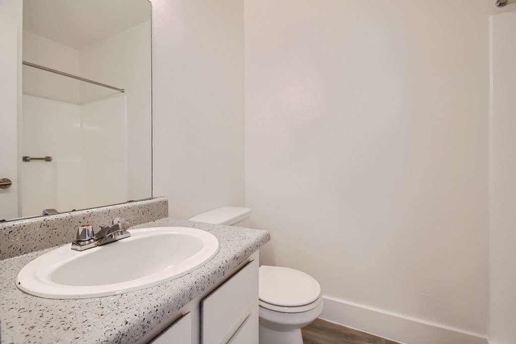 A bathroom with a sink, toilet and mirror.