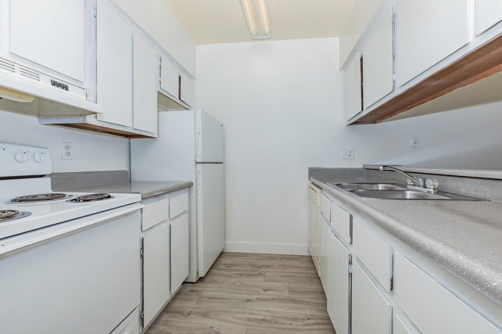 A kitchen with white cabinets and a stove top oven.