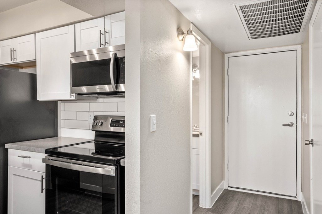 A black and white kitchen with a stove, oven, microwave, and cabinets.