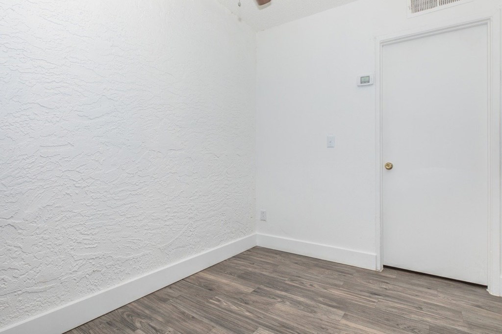 A room with a white door and wooden floor.