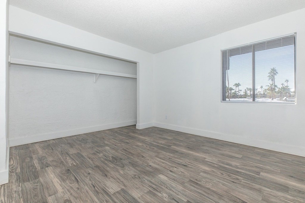 Empty room with a window and wooden flooring.