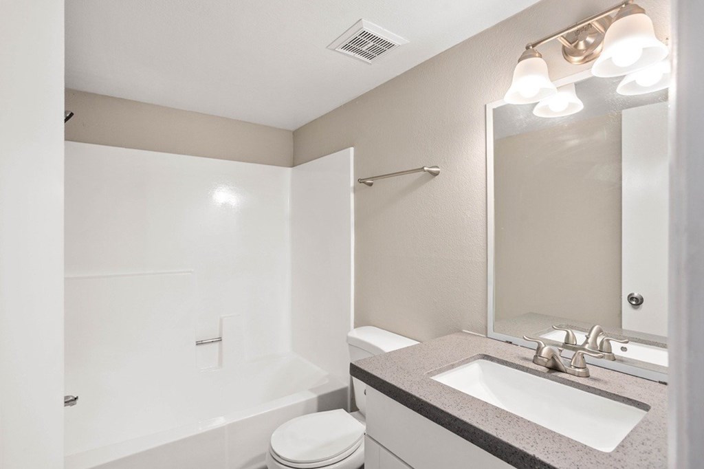 A white bathroom with a toilet, sink, and mirror.