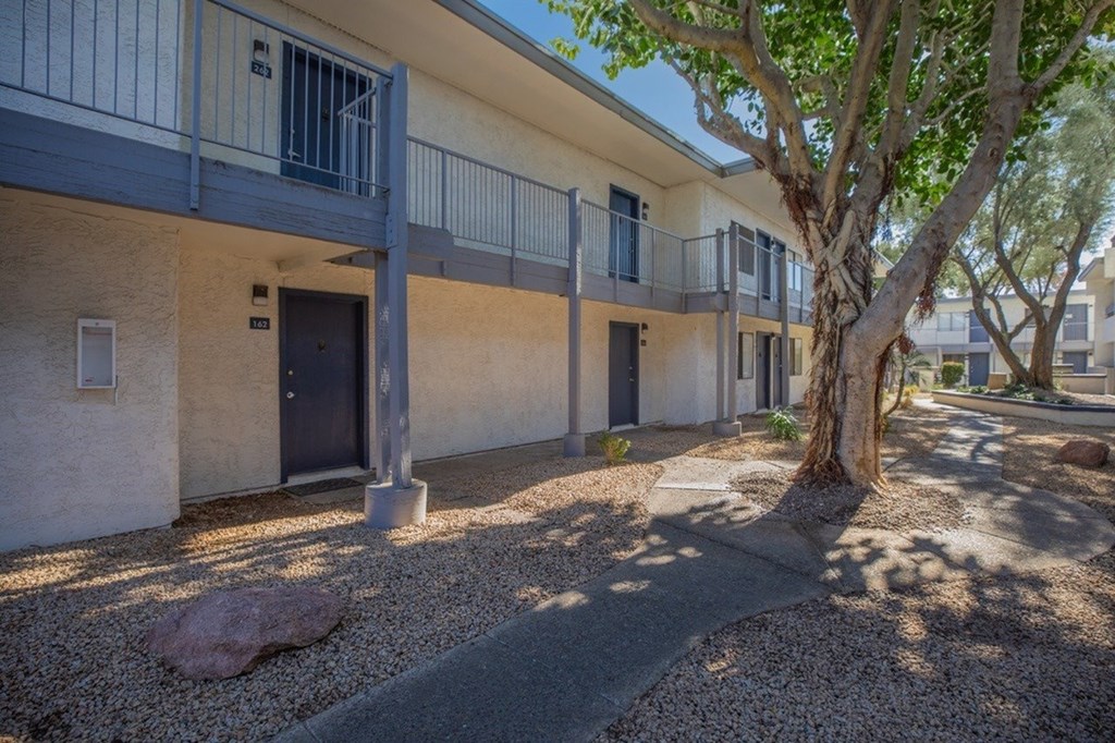 A tree is in front of a building with a balcony.