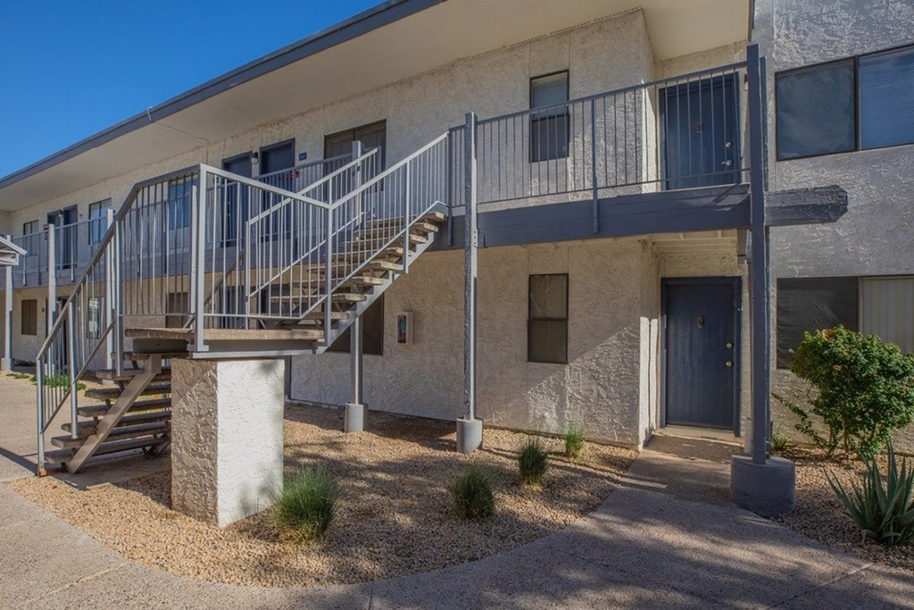 A concrete staircase with metal railings leads up to a balcony on the second floor of a building.