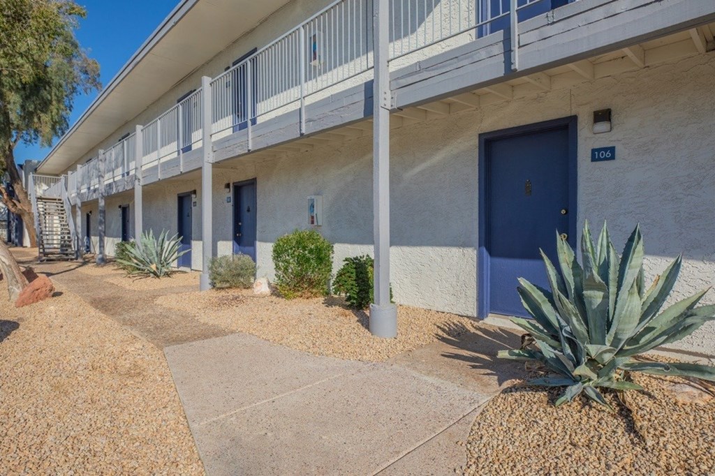A building with blue doors and windows is surrounded by plants and trees.