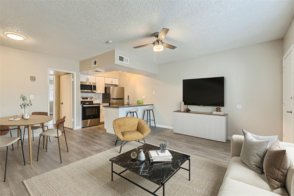 A living room with a couch, chairs, and a television.
